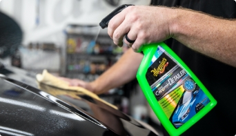 Man cleaning a vehicle with car polisher.