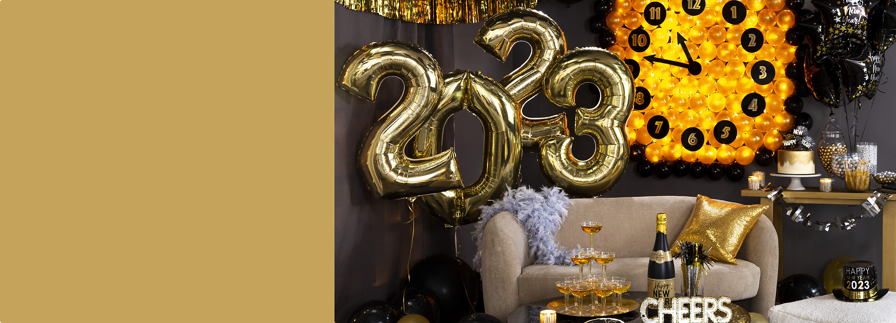 A living room filled with NYE décor including giant gold 2022 foil helium-filled number balloons and a champagne bottle confetti popper.