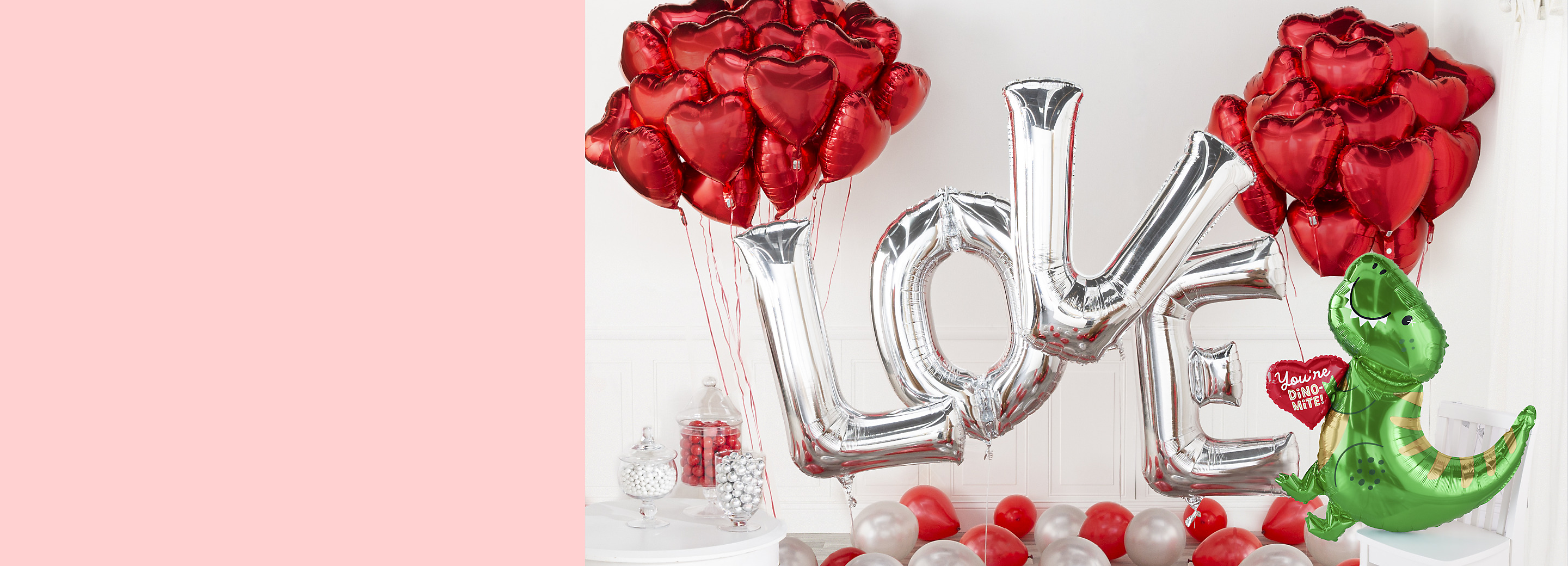A room filled with silver L-O-V-E letter balloons, a cluster of red heart foil balloons, a You’re Dino-Mite dinosaur-themed balloon.