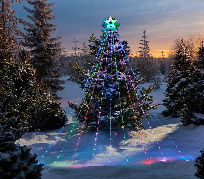 Multicolour shooting star light display arranged in a cone shape and illuminated in a snowy outdoor setting at dusk.