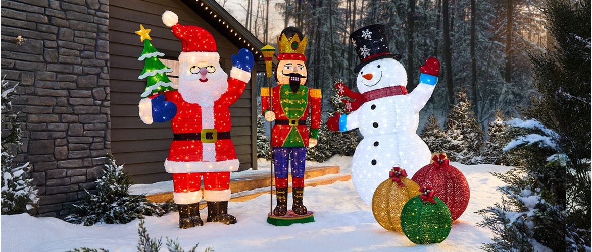 .Large outdoor holiday display featuring illuminated Santa, nutcracker, snowman and ornament decorations in a snowy landscape.