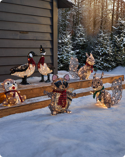 Woodland-inspired holiday decor featuring illuminated animal figures displayed in a snowy outdoor setting.