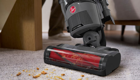 Cordless Hoover vacuum cleaning dirt and debris from carpet, demonstrating powerful suction and deep carpet cleaning performance.