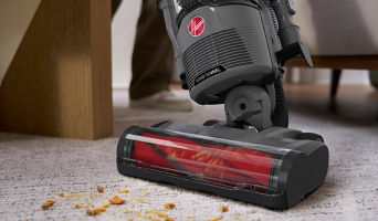Cordless Hoover vacuum cleaning dirt and debris from carpet, demonstrating powerful suction and deep carpet cleaning performance.