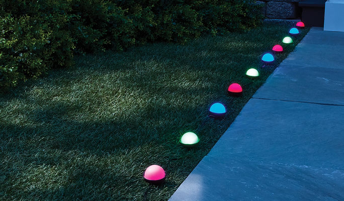 Multi-coloured NOMA Smart Ground Stake Lights installed along a residential walkway, creating a customizable lighting display that can be used throughout the year.