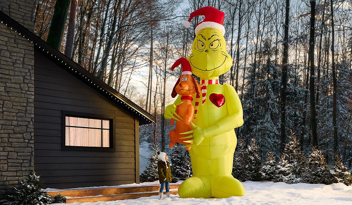 An inflatable Grinch and Max the dog Christmas decoration displayed on a snow-covered front lawn.